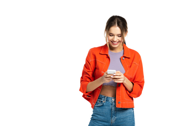 白に孤立したスマートフォンを使用して作物の上とオレンジのシャツの幸せな若い女性 - 写真・画像