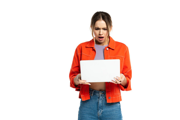 shocked young woman holding laptop isolated on white  - Фото, изображение