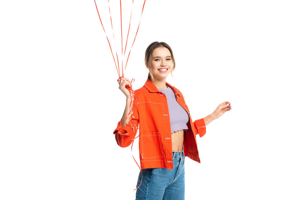 jovem feliz na camisa laranja segurando tiras de balões isolados em branco - Foto, Imagem