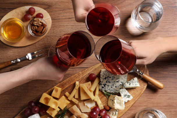 Women toasting with glasses of wine over cheese plate, top view - Valokuva, kuva