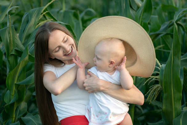 Hermosa joven madre sostiene al niño en sus manos y le pone el sombrero. Sensibilidad de la maternidad. - Foto, Imagen