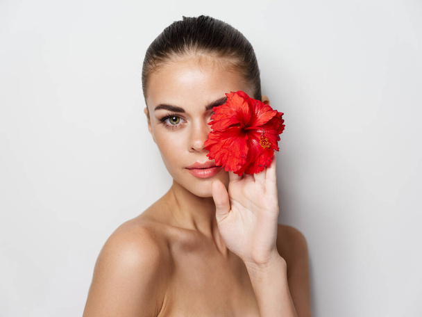 目の前に赤い花と裸の肩を持つ美しい女性が切り取られた景色 - 写真・画像