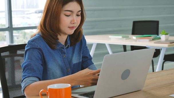 Woman working from home on laptop online meeting in home office. Entrepreneur asian business woman using notebook laptop sit on sofa technology new normal lifestyle. Happy woman typing keyboard laptop - Photo, Image