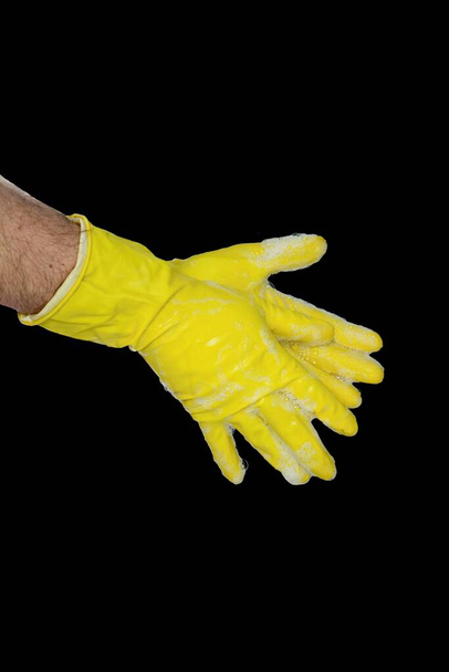 Primer plano de las manos masculinas con guantes de goma amarilla delante del fondo negro. Lávese las manos con agua tibia y jabón. - Foto, imagen