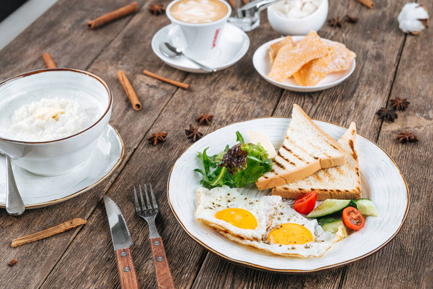 Table with breakfast of fried eggs and porridge - Фото, зображення