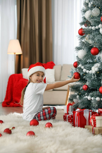 Cute little girl decorating Christmas tree at home - Foto, Imagem