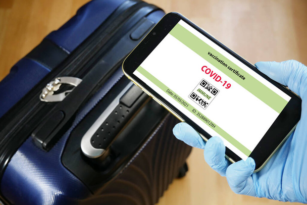 Vaccinatie paspoort op een mobiele telefoon waarmee reizen in de hand. Vaccinatie tegen het coronavirus Covid 19.Immuniteit of Gezondheid paspoort, close-up - Foto, afbeelding