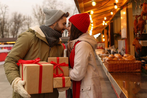 Lovely couple with Christmas presents at winter fair - Фото, зображення