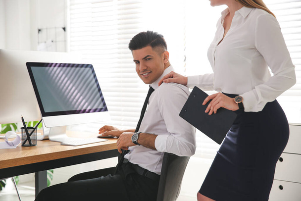 Młoda kobieta flirtuje ze swoim kolegą podczas pracy w biurze - Zdjęcie, obraz