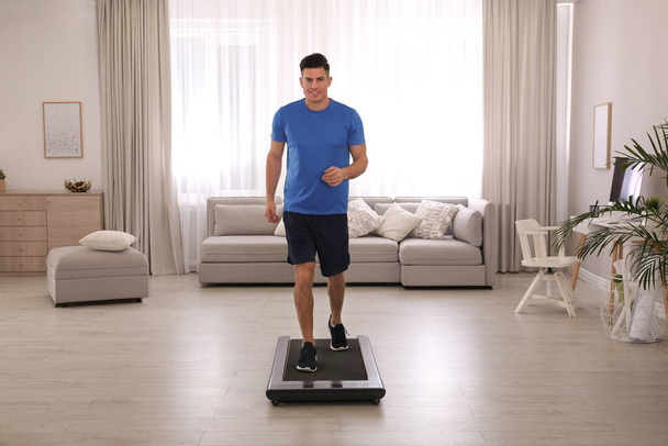 Sporty man training on walking treadmill at home - Fotó, kép