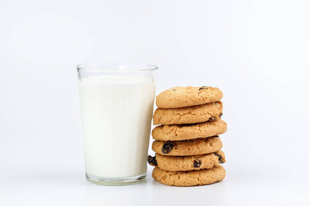 Un vaso de leche y galletas con pasas sobre fondo blanco - Foto, Imagen