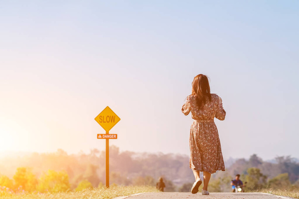 Imagem desfocada, uma mulher vestindo um vestido floral vintage caminha na rua sozinha pela manhã na solidão. Uma jovem caminha sozinha pelo corredor com a solidão no fundo do céu limpo - Foto, Imagem