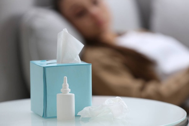 Ill woman at home, focus on nasal spray and box of tissues - Fotó, kép