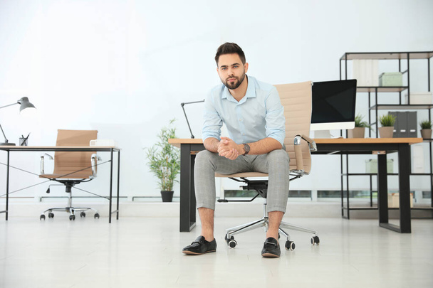 Young businessman sitting in office chair at workplace. Space for text - Foto, Imagen