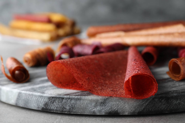 Delicious fruit leather rolls on grey table, closeup - Valokuva, kuva