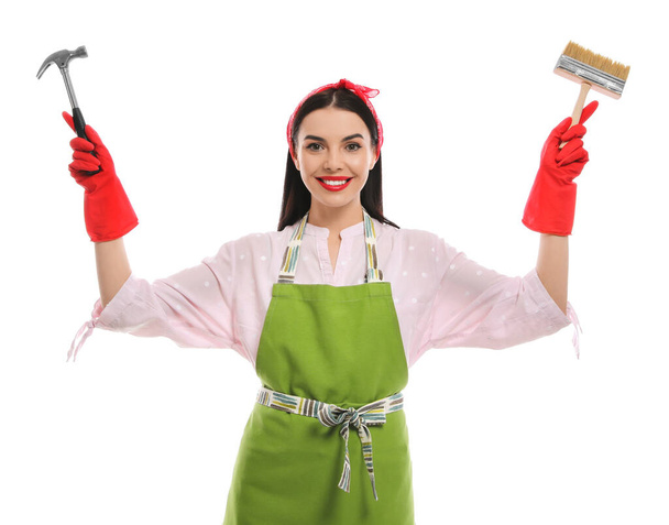Young housewife with hammer and brush on white background - Valokuva, kuva