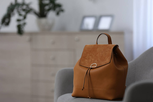 Stylish brown backpack on grey armchair indoors, space for text - Valokuva, kuva