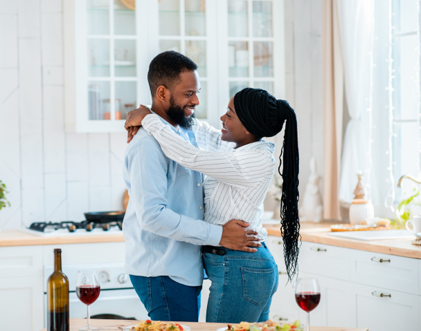 feliz casal preto abraçando na cozinha enquanto tendo data em casa - Foto, Imagem