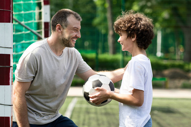 Sportowy dorosły tata gra w piłkę nożną ze swoim synem - Zdjęcie, obraz