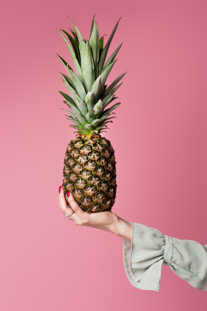 Cropped view of woman holding pineapple isolated on pink  - Photo, Image