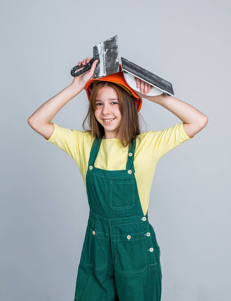 cheerful teen girl in working uniform and helmet spatula, plasterer - Foto, imagen