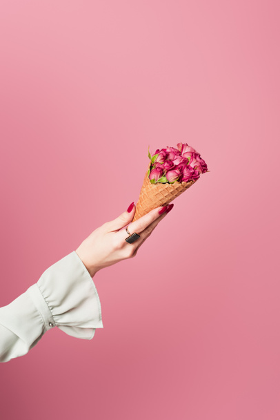 Cropped view of woman holding waffle cone with rose flowers isolated on pink  - Photo, Image