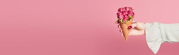 Cropped view of woman holding waffle cone with roses in hand isolated on pink, banner  - Foto, Bild