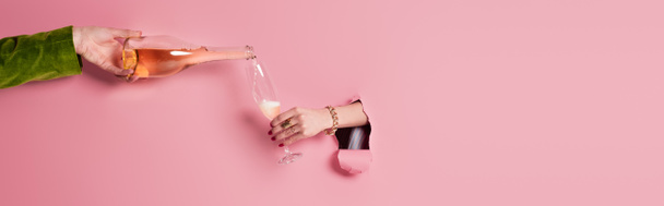 Ausgeschnittene Ansicht eines Mannes, der Champagner in der Nähe einer Frau einschenkt, mit Glas im Loch des rosafarbenen Hintergrunds, Banner  - Foto, Bild