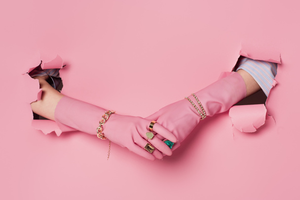 Vágott kilátás nő gyűrűk, karkötők és kesztyűk közelében rózsaszín háttér lyukak  - Fotó, kép
