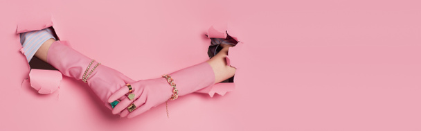 Gesneden weergave van de handen van de vrouw in handschoenen en accessoires in de buurt van roze achtergrond met gaten, banner  - Foto, afbeelding