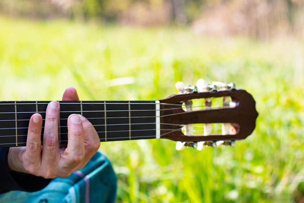 Detail Hippy muž hraje na kytaru venku na trávě - Fotografie, Obrázek