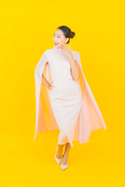 Portrait beautiful young asian woman smile with many action on yellow background - Foto, Imagen