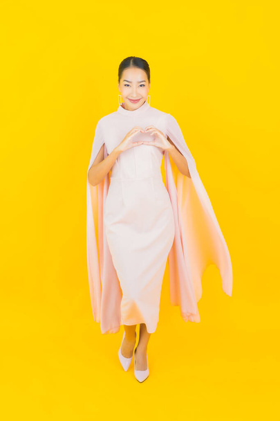 Retrato bonito jovem asiático mulher sorriso com muitos ação no fundo amarelo - Foto, Imagem