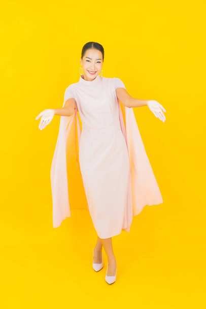 Retrato hermosa joven mujer asiática sonrisa con muchos acción sobre fondo amarillo - Foto, imagen