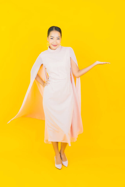 Портрет красива молода азіатка посміхається з багатьма діями на жовтому тлі
 - Фото, зображення