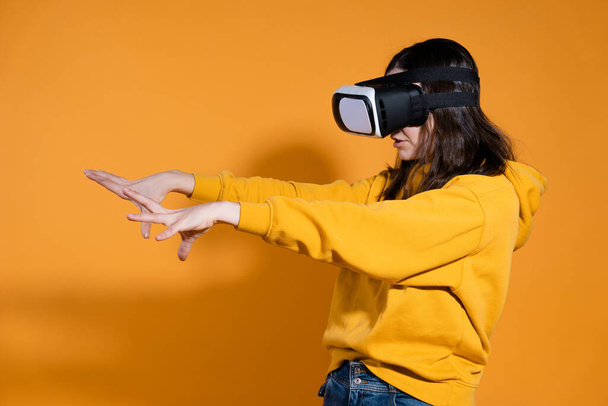 young woman with a virtual reality device on a yellow background. - Фото, зображення