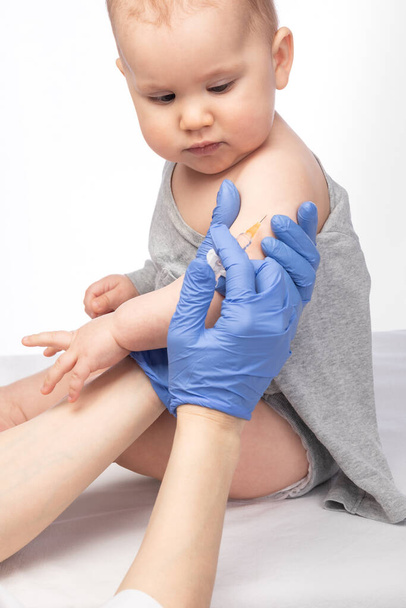 Pediatrician or nurse giving an intramuscular injection of a vaccine to arm of a baby girl during coronavirus COVID-19 pandemic - Valokuva, kuva