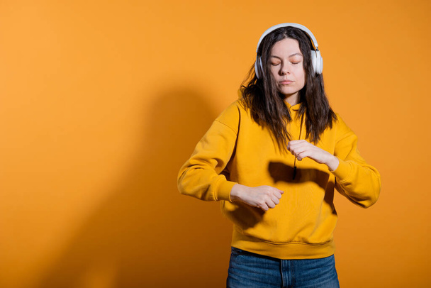 Music lovers enjoy music. A young woman in a yellow hoodie with white wireless headphones, - Fotoğraf, Görsel