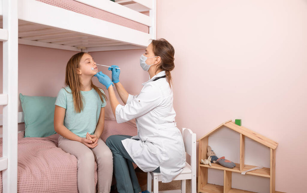 Pediatrician taking nasal mucus test sample from elementary age girl's nose performing respiratory virus testing procedure at home during coronavirus COVID-19 pandemic quarantine - Photo, Image