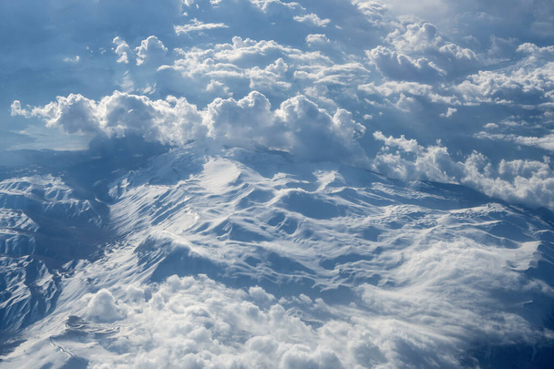 Kilátás nagy magasságból a felhők között a hegyekbe és a földre, a légtömegek mozgása. Koncepció: Isten látképe a földről, látkép a síkablakból. - Fotó, kép