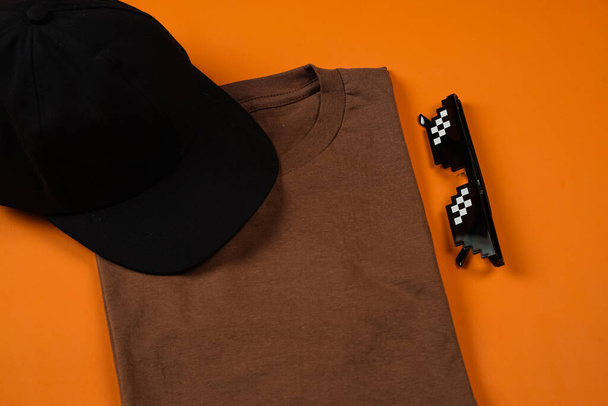 Camiseta marrón liso aislado sobre fondo naranja se suma a la impresión elegante. Las camisetas de algodón son muy cómodas para el uso diario. Espacio vacío para tu anuncio. Camiseta maqueta. - Foto, imagen
