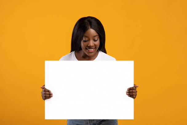 Pretty black woman holding blank board for advertisement - Foto, Imagen
