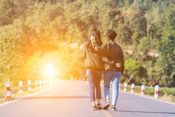 Smooth Focus, Valentine ζευγάρια που περπατούν χέρι-χέρι, κατά μήκος του δρόμου με το Χρυσό φως να έρχεται κατευθείαν από μπροστά και υποσχέθηκε να φροντίζει ο ένας τον άλλον με αγάπη και φροντίδα. Εραστές αγάπη έννοια. - Φωτογραφία, εικόνα