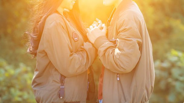 Valentijnskoppels praten en staan hand in hand op een wazige achtergrond in de ochtend om te beloven voor elkaar te zorgen met liefde en zorg voor altijd. Het concept van liefde en vriendschap - Foto, afbeelding