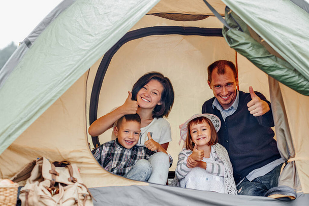 Rodzice rodziny i dwójka dzieci w namiocie obozowym. Szczęśliwa matka, ojciec, syn i córka na wakacjach letnich. - Zdjęcie, obraz