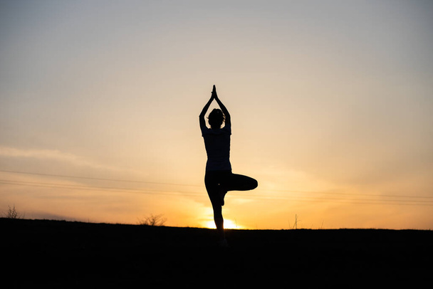 žena v rovnováze póza při západu slunce jóga venku - Fotografie, Obrázek