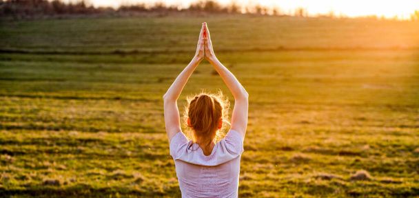 vrouw in een balancerende houding bij zonsondergang yoga buiten - Foto, afbeelding
