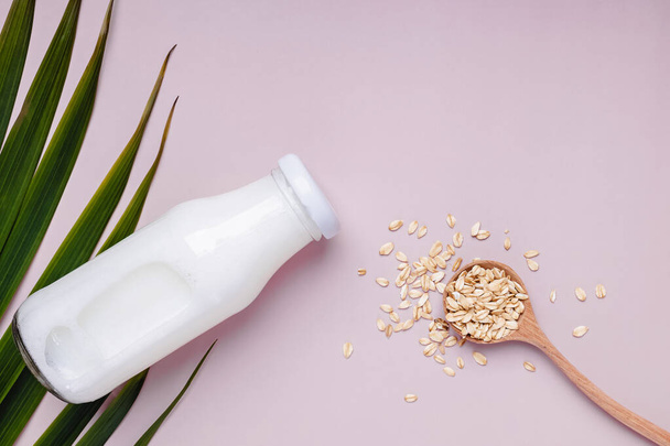 Bottle with daity free oat milk and dry oats in the spoon. - Photo, image