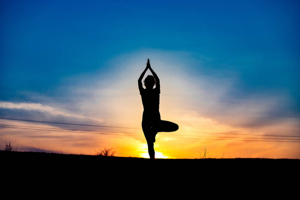 nő egy kiegyensúlyozó pózban a naplemente jóga szabadban - Fotó, kép