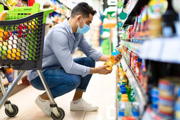 Близькосхідний чоловік робить продуктовий магазин Вибираючи олію в супермаркеті
 - Фото, зображення